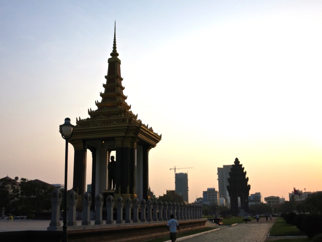 Walking along the park on Preah Suramarit Boulevard; King Norodom Sihanouk Statue and Independence Monument behind